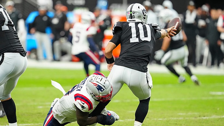 Oct 15, 2023; Paradise, Nevada, USA; Las Vegas Raiders quarterback Jimmy Garoppolo (10) flips the ball away to avoid being sacked by New England Patriots linebacker Ja'Whaun Bentley (8) during the second quarter at Allegiant Stadium. Mandatory Credit: Stephen R. Sylvanie-USA TODAY Sports
