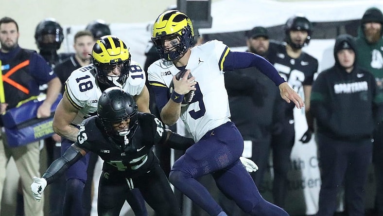Michigan Wolverines quarterback J.J. McCarthy (9) runs by Michigan State Spartans defensive back Malik Spencer (43) during first-half action at Spartan Stadium in East Lansing on Saturday, Oct. 21, 2023.