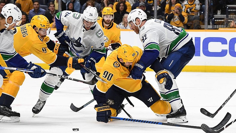 Oct 24, 2023; Nashville, Tennessee, USA; Nashville Predators center Ryan O'Reilly (90) is hit by Vancouver Canucks defenseman Ian Cole (82) as he handles the puck in front of the net during the third period at Bridgestone Arena. Mandatory Credit: Christopher Hanewinckel-USA TODAY Sports