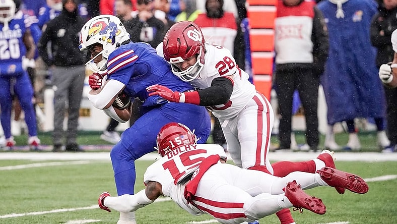 Oct 28, 2023; Lawrence, Kansas, USA; Kansas Jayhawks running back Devin Neal (4) runs the ball as Oklahoma Sooners linebacker Danny Stutsman (28) and defensive back Kendel Dolby (15) make the tackle during the first half at David Booth Kansas Memorial Stadium. Mandatory Credit: Denny Medley-USA TODAY Sports