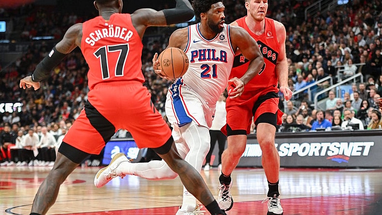 Oct 28, 2023; Toronto, Ontario, CAN;  Philadelphia 76ers center Joel Embiid (21) drives to the basket between Toronto Raptors center Jakob Poeltl (19) and guard Dennis Schroder (17) in the first half at Scotiabank Arena. Mandatory Credit: Dan Hamilton-USA TODAY Sports