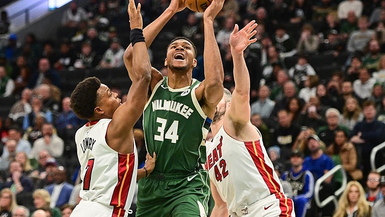 Oct 30, 2023; Milwaukee, Wisconsin, USA;  Milwaukee Bucks forward Giannis Antetokounmpo (34) takes a shot between Miami Heat guard Kyle Lowry (7) and forward Kevin Love (42) in the first quarter at Fiserv Forum. Mandatory Credit: Benny Sieu-USA TODAY Sports