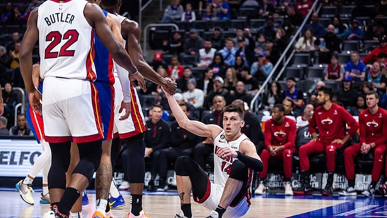 Mar 19, 2023; Detroit, Michigan, USA; Miami Heat guard Tyler Herro (14) is helped to his feet by center Bam Adebayo (13) in the first quarter against the Detroit Pistons at Little Caesars Arena. Mandatory Credit: Allison Farrand-USA TODAY Sports
