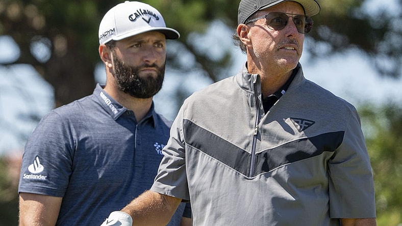 July 19, 2023; Hoylake, ENGLAND, GBR; Jon Rahm (left) watches the tee shot of Phil Mickelson (right) on the 18th hole during a practice round of The Open Championship golf tournament at Royal Liverpool. Mandatory Credit: Kyle Terada-USA TODAY Sports