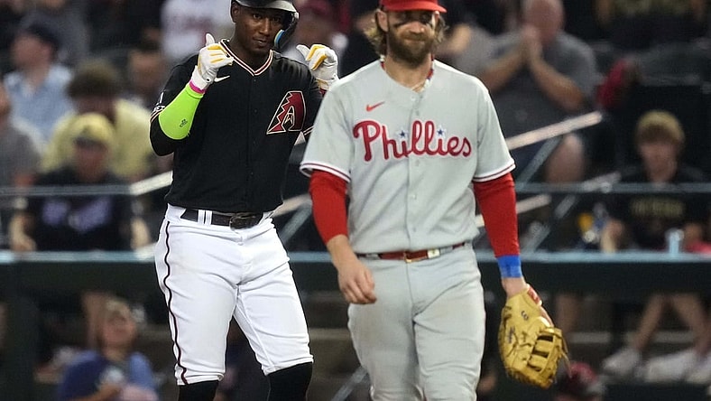Arizona Diamondbacks shortstop Geraldo Perdomo (left) reacts after hitting a single during the seventh inning as Philadelphia Phillies first baseman Bryce Harper (right) looks on in game four of the NLCS of the 2023 MLB playoffs at Chase Field in Phoenix on Oct. 20, 2023.
