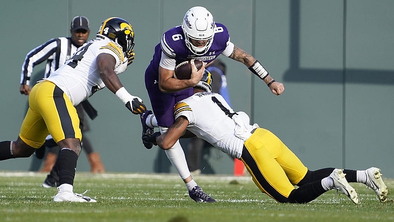 Nov 4, 2023; Chicago, Illinois, USA; Iowa Hawkeyes defensive back Xavier Nwankpa (1) tackles Northwestern Wildcats quarterback Brendan Sullivan (6) during the first half at Wrigley Field. Mandatory Credit: David Banks-USA TODAY Sports