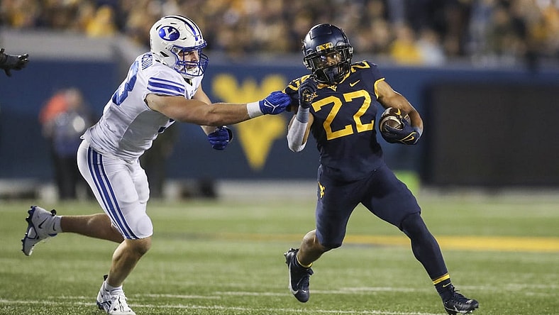 Nov 4, 2023; Morgantown, West Virginia, USA; West Virginia Mountaineers running back Jahiem White (22) runs the ball and avoids a tackle from Brigham Young Cougars defensive end Blake Mangelson (93) during the second quarter at Mountaineer Field at Milan Puskar Stadium. Mandatory Credit: Ben Queen-USA TODAY Sports