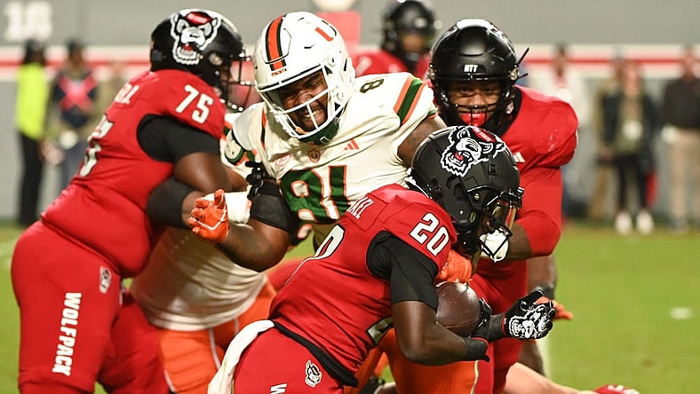Nov 4, 2023; Raleigh, North Carolina, USA; North Carolina State Wolfpack running back Kendrick Raphael (20) runs as Miami Hurricanes defensive lineman Jared Harrison-Hunte (81) defends during the first half at Carter-Finley Stadium. Mandatory Credit: Rob Kinnan-USA TODAY Sports