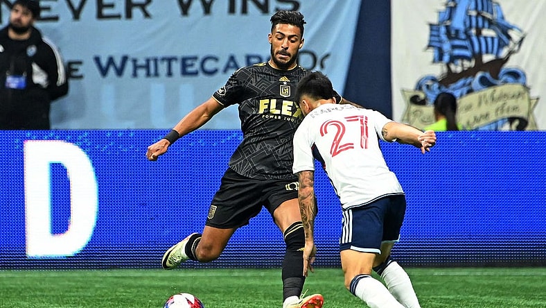 Nov 5, 2023; Vancouver, British Columbia, CAN; Los Angeles FC forward Denis Bouanga (99) kicks the ball against Vancouver Whitecaps midfielder Ryan Raposo (27) during the second half of game two in a round one match of the 2023 MLS Cup Playoffs at BC Place. Mandatory Credit: Simon Fearn-USA TODAY Sports