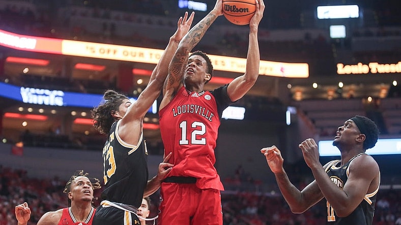 Louisville Cardinals forward JJ Traynor (12) gets fouled by UMBC Retrievers guard Dion Brown (13) Monday night at the Cardinals men's basketball season opener. Nov.6, 2023.