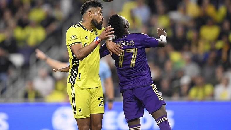 Nov 7, 2023; Nashville, Tennessee, USA; Nashville SC midfielder Anibal Godoy (20) heads the ball against Orlando City forward Ivan Angulo (77) in the second half at Geodis Park. Mandatory Credit: Steve Roberts-USA TODAY Sports