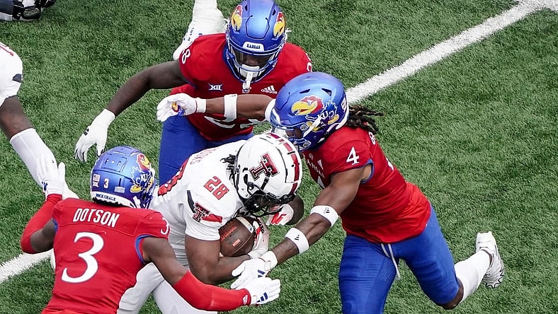 Nov 11, 2023; Lawrence, Kansas, USA; Kansas Jayhawks cornerback Mello Dotson (3) and safety Marvin Grant (4) tackle Texas Tech Red Raiders running back Tahj Brooks (28) during the first half at David Booth Kansas Memorial Stadium. Mandatory Credit: Denny Medley-USA TODAY Sports