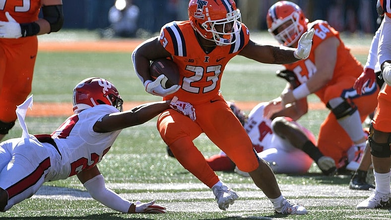 Nov 11, 2023; Champaign, Illinois, USA;  Illinois Fighting Illini running back Reggie Love III (23) eludes the tackle of Indiana Hoosiers defensive back Louis Moore (20) during the first half at Memorial Stadium. Mandatory Credit: Ron Johnson-USA TODAY Sports