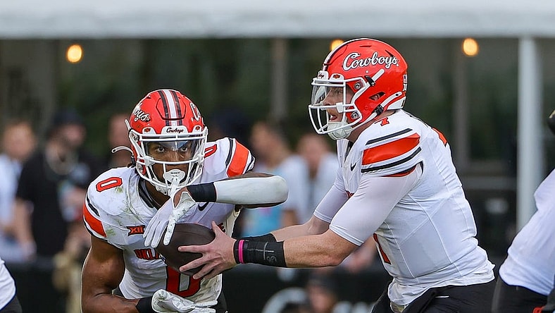 Nov 11, 2023; Orlando, Florida, USA; Oklahoma State Cowboys quarterback Alan Bowman (7) hands off to running back Ollie Gordon II (0) during the first quarter against the UCF Knights at FBC Mortgage Stadium. Mandatory Credit: Mike Watters-USA TODAY Sports