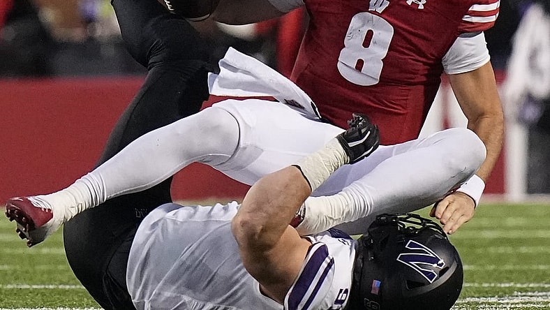 Nov 11, 2023; Madison, Wisconsin, USA; Wisconsin quarterback Tanner Mordecai (8) is sacked by Northwestern defensive lineman Aidan Hubbard (91) during the third quarter at Camp Randall Stadium. Mandatory Credit: Mark Hoffman-USA TODAY Sports