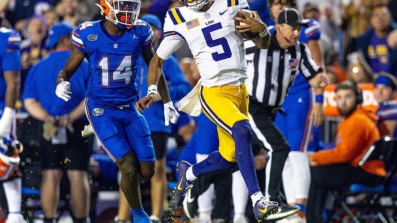 Nov 11, 2023; Baton Rouge, Louisiana, USA;  LSU Tigers quarterback Jayden Daniels (5) rushes for a touchdown against Florida Gators safety Jordan Castell (14) during the first half at Tiger Stadium. Mandatory Credit: Stephen Lew-USA TODAY Sports