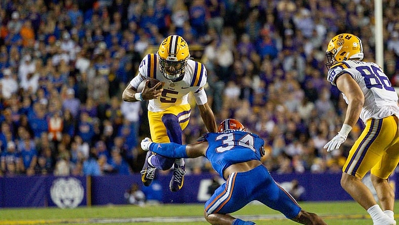 Nov 11, 2023; Baton Rouge, Louisiana, USA;  LSU Tigers quarterback Jayden Daniels (5) attempts to leap over the arms of Florida Gators linebacker Mannie Nunnery (34) during the first half at Tiger Stadium. Mandatory Credit: Stephen Lew-USA TODAY Sports