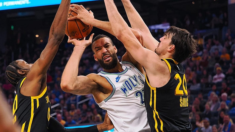 Nov 12, 2023; San Francisco, California, USA; Minnesota Timberwolves center Rudy Gobert (27) controls th ball against Golden State Warriors forward Jonathan Kuminga (00) and forward Dario Saric (20) during the second quarter at Chase Center. Mandatory Credit: Kelley L Cox-USA TODAY Sports