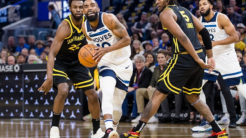 Nov 14, 2023; San Francisco, California, USA; Minnesota Timberwolves guard Mike Conley (10) prepares to shoot in front of Golden State Warriors forward Kevon Looney (5) and forward Andrew Wiggins (22) during the first half at Chase Center. Mandatory Credit: John Hefti-USA TODAY Sports