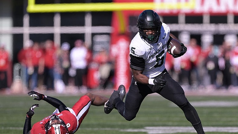 Nov 18, 2023; Bloomington, Indiana, USA;  Michigan State Spartans running back Nathan Carter (5) evades tackle by Indiana Hoosiers defensive back Phillip Dunnam (6) during the first quarter at Memorial Stadium. Mandatory Credit: Marc Lebryk-USA TODAY Sports