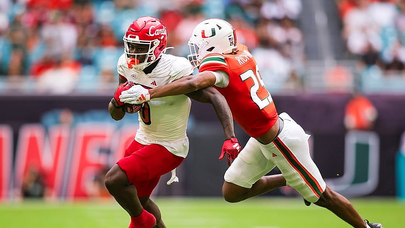 Nov 18, 2023; Miami Gardens, Florida, USA; Louisville Cardinals wide receiver Chris Bell (0) breaks a tackle attempt from Miami Hurricanes defensive back Jadais Richard (25) during the second quarter at Hard Rock Stadium. Mandatory Credit: Sam Navarro-USA TODAY Sports