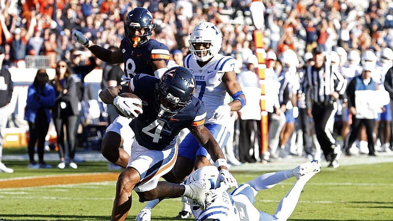 Nov 18, 2023; Charlottesville, Virginia, USA; Virginia Cavaliers wide receiver Malik Washington (4) scores a touchdown as Duke Blue Devils safety Jaylen Stinson (2) chases during the first quarter at Scott Stadium. Mandatory Credit: Geoff Burke-USA TODAY Sports
