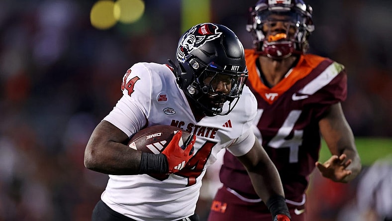 Nov 18, 2023; Blacksburg, Virginia, USA; North Carolina State Wolfpack running back Delbert Mimms III (34) runs the ball against Virginia Tech Hokies linebacker Alan Tisdale (34) during the third quarter at Lane Stadium. Mandatory Credit: Peter Casey-USA TODAY Sports