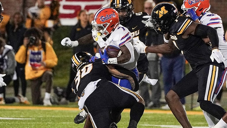 Nov 18, 2023; Columbia, Missouri, USA; Florida Gators running back Trevor Etienne (7) runs the ball as Missouri Tigers linebacker Chuck Hicks (30) makes the tackle during the first half at Faurot Field at Memorial Stadium. Mandatory Credit: Denny Medley-USA TODAY Sports