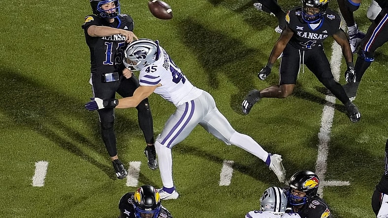 Nov 18, 2023; Lawrence, Kansas, USA; Kansas Jayhawks quarterback Cole Ballard (15) throws a touchdown pass as he is hit by Kansas State Wildcats linebacker Austin Romaine (45) during the first half at David Booth Kansas Memorial Stadium. Mandatory Credit: Jay Biggerstaff-USA TODAY Sports