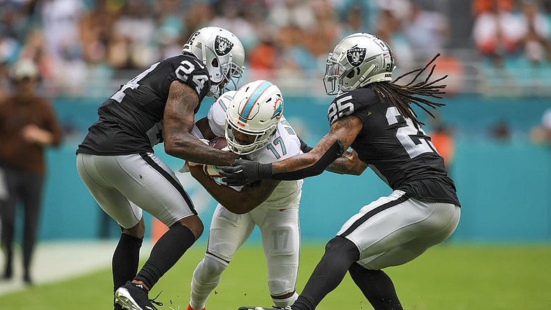 Nov 19, 2023; Miami Gardens, Florida, USA; Miami Dolphins wide receiver Jaylen Waddle (17) runs with the football as Las Vegas Raiders cornerback Marcus Peters (24) and safety Tre'von Moehrig (25) attempt to him during the second quarter at Hard Rock Stadium. Mandatory Credit: Sam Navarro-USA TODAY Sports