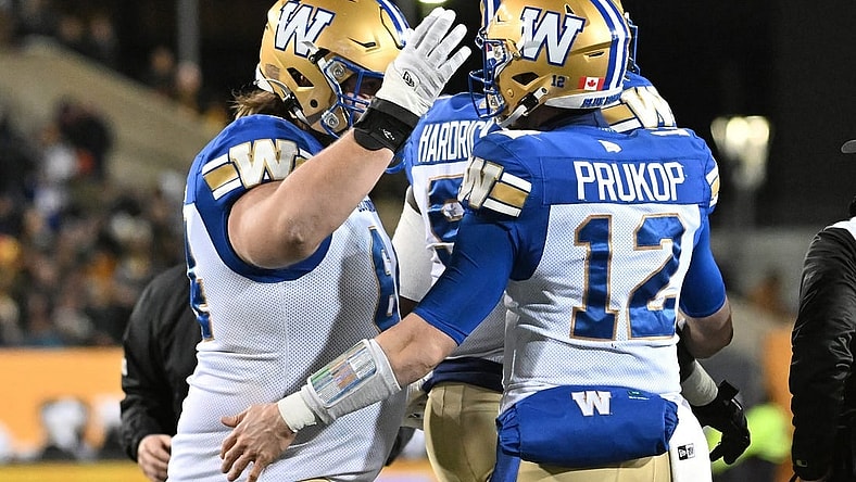 Nov 19, 2023; Hamilton, Ontario, CAN;  Winnipeg Blue Bombers quarterback Dakota Prukop (12) celebrates with offensive lineman Liam Dobson (64) after scoring a touchdown against the Montreal Alouettes in the first half at Tim Hortons Field. Mandatory Credit: Dan Hamilton-USA TODAY Sports