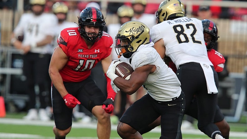 Nov 18, 2023; Lubbock, Texas, USA;  Central Florida Knights running back RJ Harvey (7) rushes against Texas Tech Red Raiders defensive end Jacob Rodriguez (10) in the first half at Jones AT&T Stadium and Cody Campbell Field. Mandatory Credit: Michael C. Johnson-USA TODAY Sports