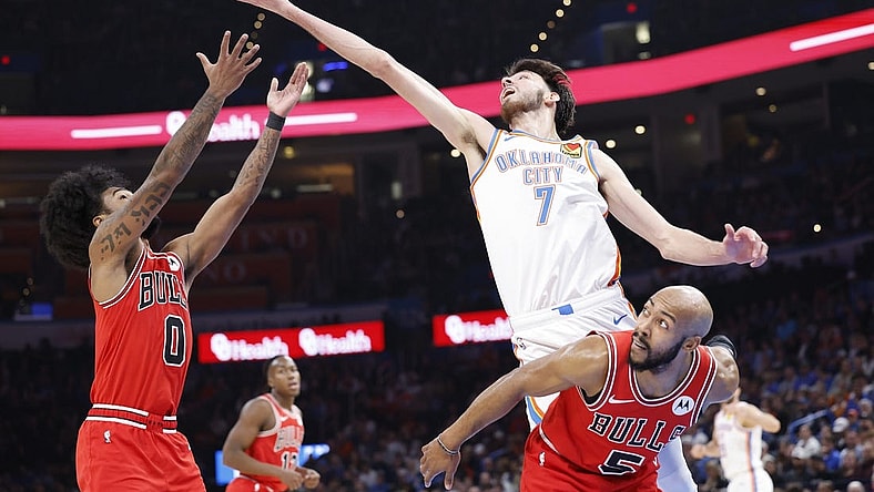 Nov 22, 2023; Oklahoma City, Oklahoma, USA; Oklahoma City Thunder forward Chet Holmgren (7) reaches for a loose ball over Chicago Bulls guard Coby White (0) and guard Jevon Carter (5) during the second quarter at Paycom Center. Mandatory Credit: Alonzo Adams-USA TODAY Sports