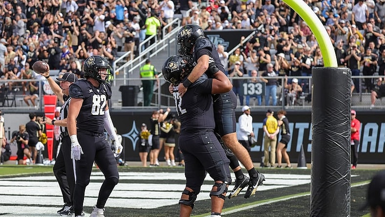 Nov 25, 2023; Orlando, Florida, USA; UCF Knights quarterback John Rhys Plumlee (10) is lifted into the air by offensive lineman Marcellus Marshall (72) after scoring against the Houston Cougars during the first quarter at FBC Mortgage Stadium. Mandatory Credit: Mike Watters-USA TODAY Sports