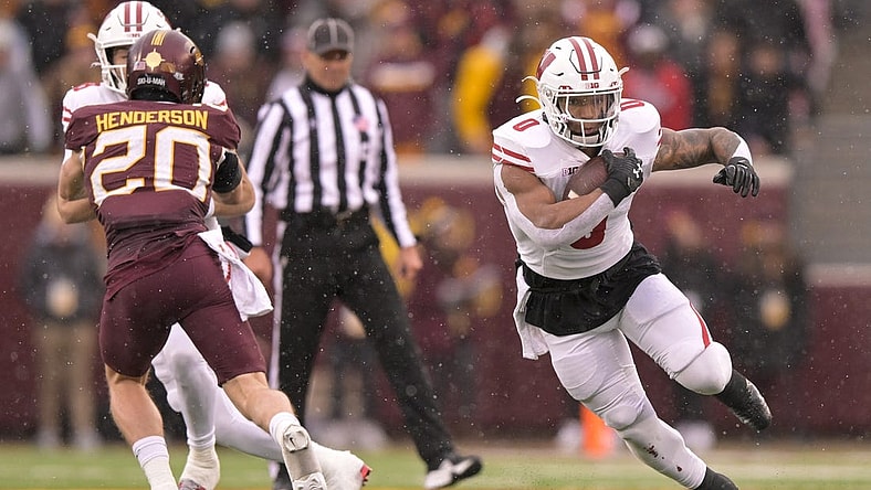Nov 25, 2023; Minneapolis, Minnesota, USA;  Wisconsin Badgers running back Braelon Allen (0) runs with the ball as quarterback Tanner Mordecai (8) puts a block on Minnesota Golden Gophers defensive back Jack Henderson (20) at Huntington Bank Stadium. Mandatory Credit: Nick Wosika-USA TODAY Sports