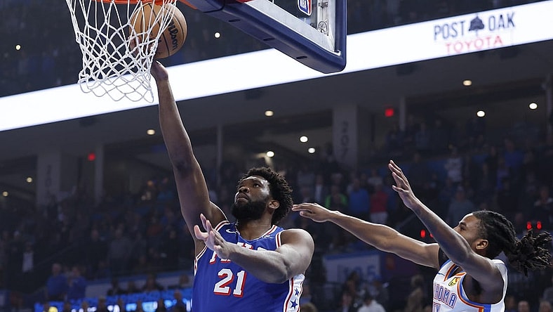 Nov 25, 2023; Oklahoma City, Oklahoma, USA; Philadelphia 76ers center Joel Embiid (21) shoots as Oklahoma City Thunder guard Cason Wallace (22) defends during the first quarter at Paycom Center. Mandatory Credit: Alonzo Adams-USA TODAY Sports