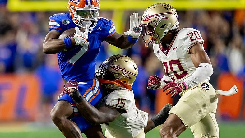 Florida Gators running back Trevor Etienne (7) rushes with the ball while Florida State Seminoles linebacker Tatum Bethune (15) and Florida State Seminoles defensive back Azareye'h Thomas (20) attempt to tackle during the first half at Steve Spurrier Field at Ben Hill Griffin Stadium in Gainesville, FL on Saturday, November 25, 2023. [Matt Pendleton/Gainesville Sun]
