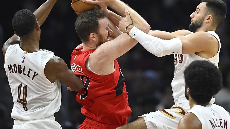 Nov 26, 2023; Cleveland, Ohio, USA; Cleveland Cavaliers forward Evan Mobley (4) and guard Max Strus (1) defend Toronto Raptors center Jakob Poeltl (19) in the second quarter at Rocket Mortgage FieldHouse. Mandatory Credit: David Richard-USA TODAY Sports