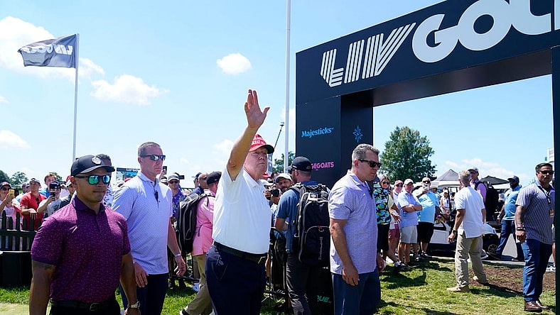 Former President Donald Trump waves to the crowd as he exits the putting green with his aide Walt Nauta, left, during the final round of the LIV Golf Bedminster golf tournament at Trump National Bedminster on Sunday, Aug. 13, 2023.