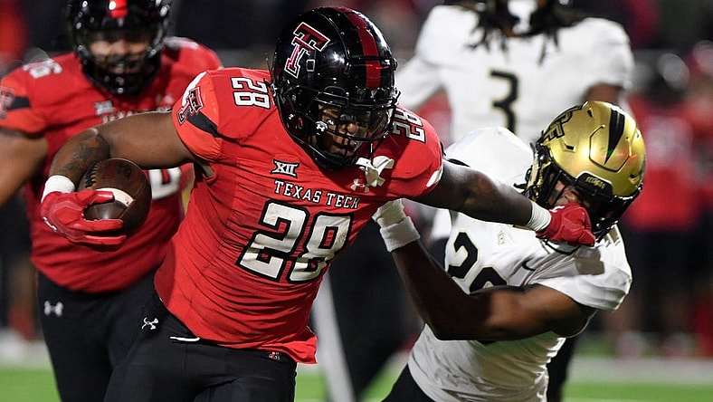 Texas Tech's running back Tahj Brooks (28) stiff-arms UCF's defensive back William Wells (29) during the Big 12 football game, Saturday, Nov. 18, 2023, at Jones AT&T Stadium.