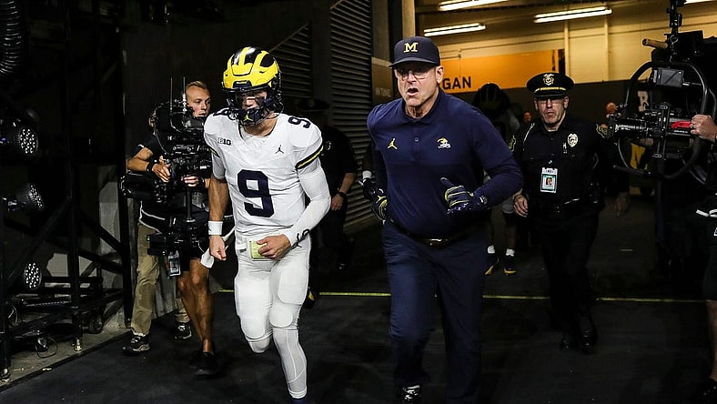 Michigan quarterback J.J. McCarthy and head coach Jim Harbaugh take the field for warmups before the Big Ten championship game vs. Iowa at Lucas Oil Stadium on Saturday, Dec. 2, 2023.