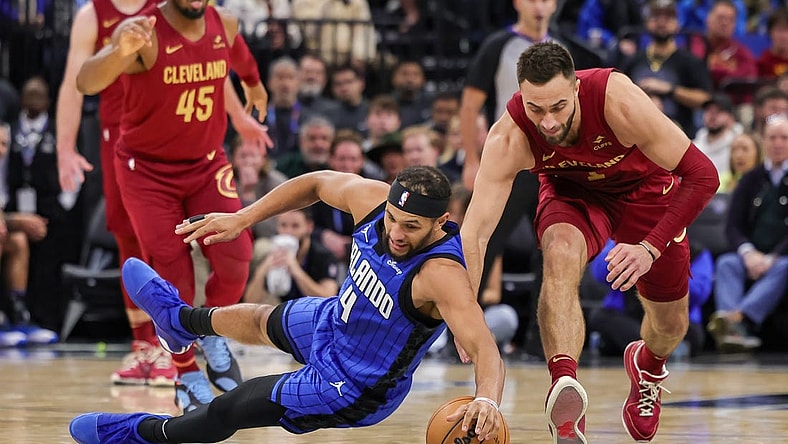 Dec 11, 2023; Orlando, Florida, USA; Orlando Magic guard Jalen Suggs (4) and Cleveland Cavaliers guard Max Strus (1) chase a loose ball during the second quarter at Amway Center. Mandatory Credit: Mike Watters-USA TODAY Sports