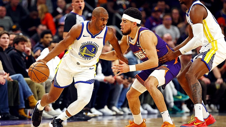 Dec 12, 2023; Phoenix, Arizona, USA; Golden State Warriors guard Chris Paul (3) drives to the basket against Phoenix Suns guard Devin Booker (1) during the first quarter at Footprint Center. Mandatory Credit: Mark J. Rebilas-USA TODAY Sports