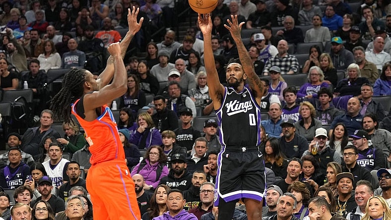 Dec 14, 2023; Sacramento, California, USA; Sacramento Kings guard Malik Monk (0) shoots against Oklahoma City Thunder guard Cason Wallace (left) during the second quarter at Golden 1 Center. Mandatory Credit: Darren Yamashita-USA TODAY Sports
