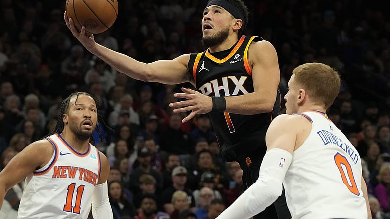 Dec 15, 2023; Phoenix, Arizona, USA; Phoenix Suns guard Devin Booker (1) drives between New York Knicks guard Jalen Brunson (11) and  guard Donte DiVincenzo (0) in the first half at Footprint Center. Mandatory Credit: Rick Scuteri-USA TODAY Sports