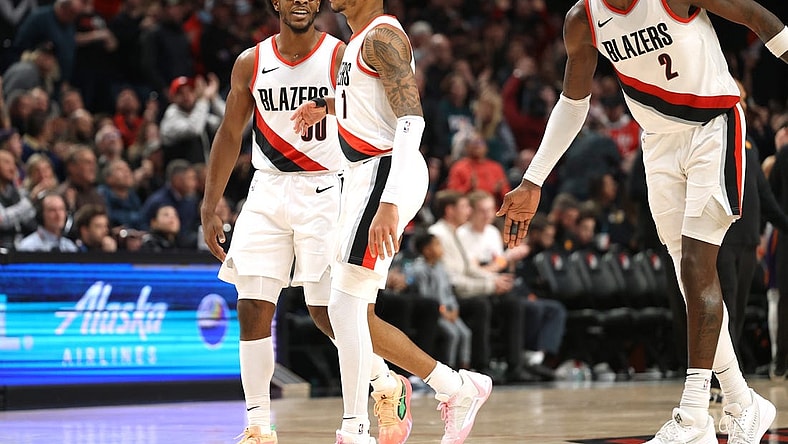 Dec 19, 2023; Portland, Oregon, USA;  Portland Trail Blazers guard Scoot Henderson (00), left, and center Deandre Ayton (2) celebrates with guard Anfernee Simons (1) after Simons scored a basket to seal the 109-104 win over Phoenix Suns at Moda Center. Mandatory Credit: Jaime Valdez-USA TODAY Sports
