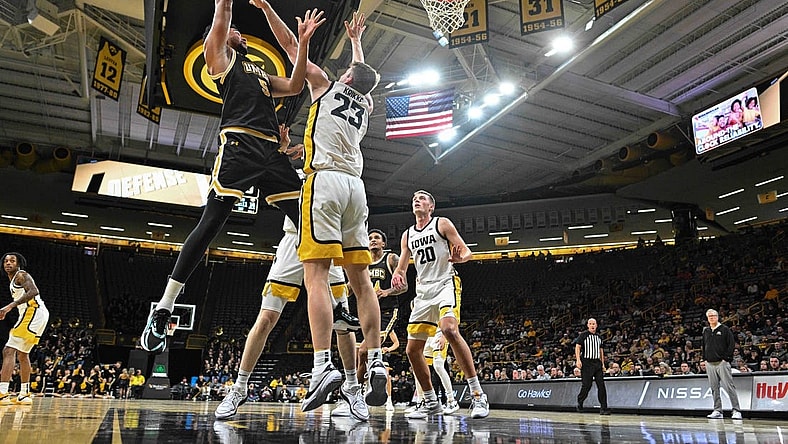 Dec 20, 2023; Iowa City, Iowa, USA; UMBC Retrievers center Max Lorca-Lloyd (5) shoots the ball over Iowa Hawkeyes forward Ben Krikke (23) and forward Payton Sandfort (20) defend during the first half at Carver-Hawkeye Arena. Mandatory Credit: Jeffrey Becker-USA TODAY Sports