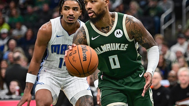 Dec 21, 2023; Milwaukee, Wisconsin, USA;  Milwaukee Bucks guard Damian Lillard (0) drives past Orlando Magic guard Gary Harris (14) in the fourth quarter at Fiserv Forum. Mandatory Credit: Benny Sieu-USA TODAY Sports