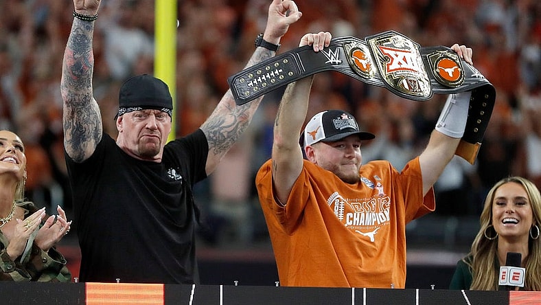 Texas's Quinn Ewers (3) holds up the WWE Big 12 Championship belt next to The Undertaker following the Big 12 Football Championship game between the Oklahoma State University Cowboys and the Texas Longhorns at the AT&T Stadium in Arlington, Texas, Saturday, Dec. 2, 2023.