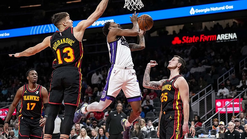 Dec 29, 2023; Atlanta, Georgia, USA; Sacramento Kings guard Malik Monk (0) tries to score past Atlanta Hawks guard Bogdan Bogdanovic (13) during the first half at State Farm Arena. Mandatory Credit: Dale Zanine-USA TODAY Sports